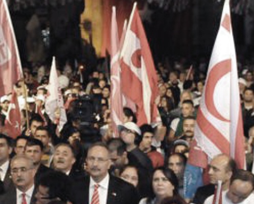 Mehmet Ali Talat'ın seçim kampanyası sırasında, rüşvet ve usulsüzlere adı karışmış o dönemde ÖP başkanı olan sonra UBP'ye dönen Turgay Avcı ile İzcan, TC-KKC bayrakları altında birçok yan yana gelip ayni kürsüyü de paylaşmışlardı